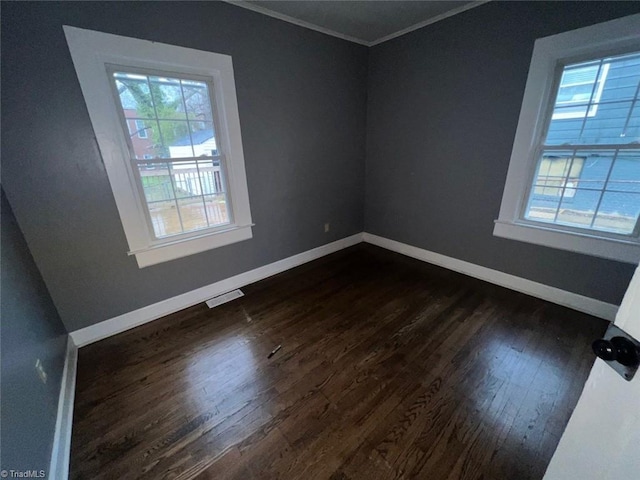 unfurnished room with dark wood finished floors, visible vents, a healthy amount of sunlight, and baseboards