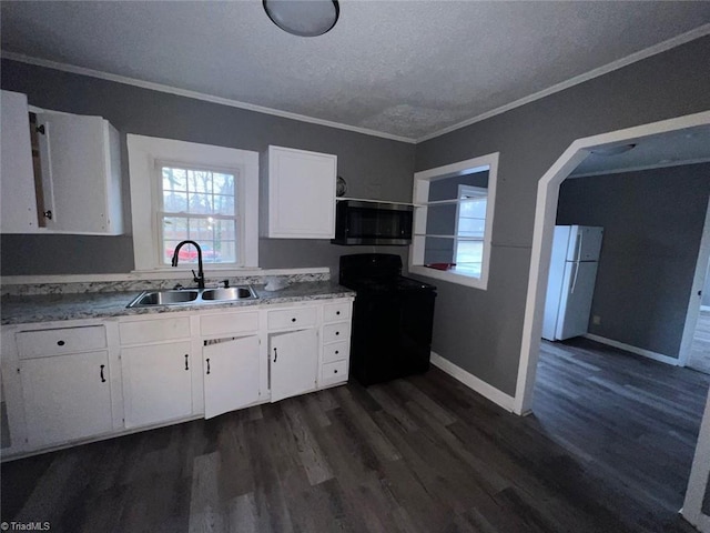 kitchen featuring stainless steel microwave, crown molding, range, freestanding refrigerator, and a sink