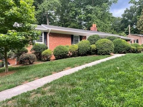 1128 Partridge Ln, Winston-Salem, NC 27106 - view of front of home featuring a front yard, a chimney, and brick siding