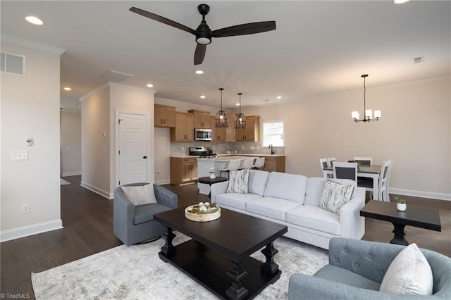 living area with dark wood-style floors, ornamental molding, visible vents, and baseboards