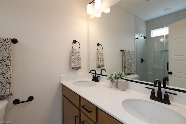 full bath featuring toilet, a stall shower, double vanity, and a sink