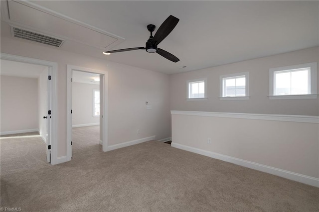 carpeted spare room with a healthy amount of sunlight, baseboards, visible vents, and attic access