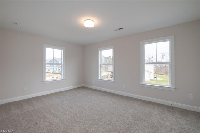 unfurnished room featuring light carpet, a wealth of natural light, and visible vents