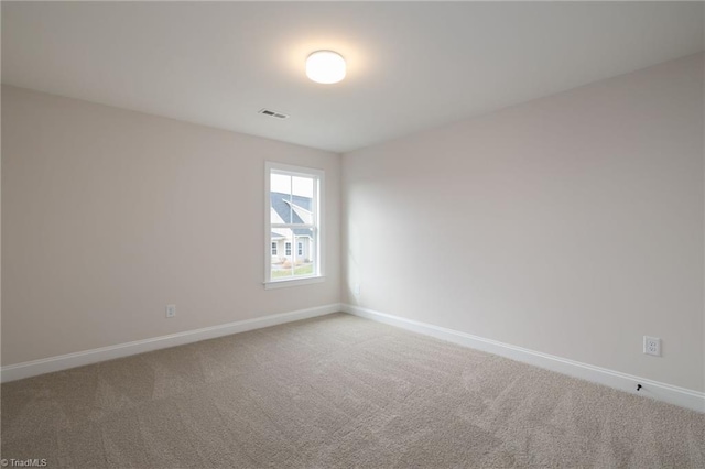 unfurnished room with carpet floors, visible vents, and baseboards