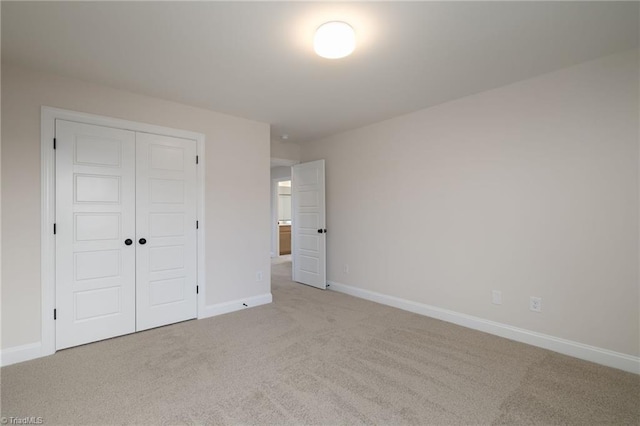 unfurnished bedroom with a closet, carpet, and baseboards