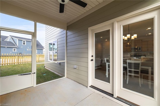 unfurnished sunroom with ceiling fan with notable chandelier