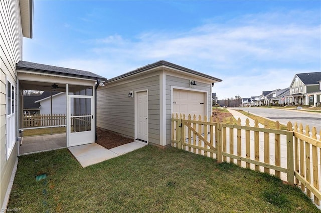 view of yard featuring a sunroom, an outdoor structure, fence, and a residential view