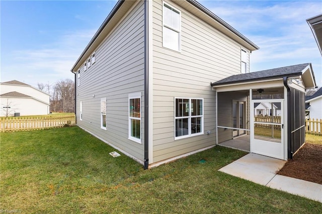 back of property with a lawn, fence, and a sunroom