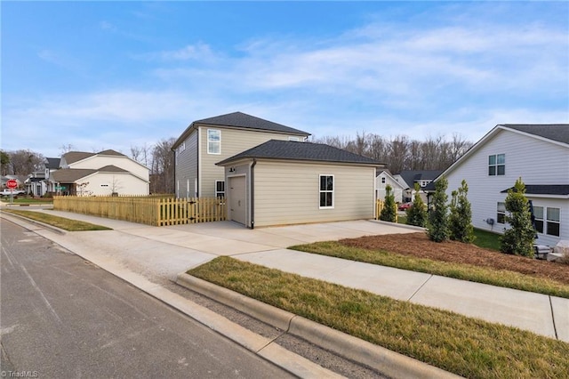 view of front of house with driveway, a garage, a residential view, an outbuilding, and fence