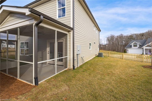 view of side of property with cooling unit, a sunroom, fence, and a lawn