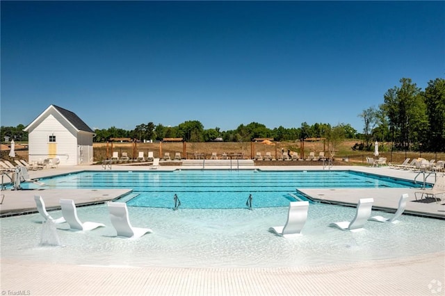 community pool featuring an outbuilding, a patio, and fence