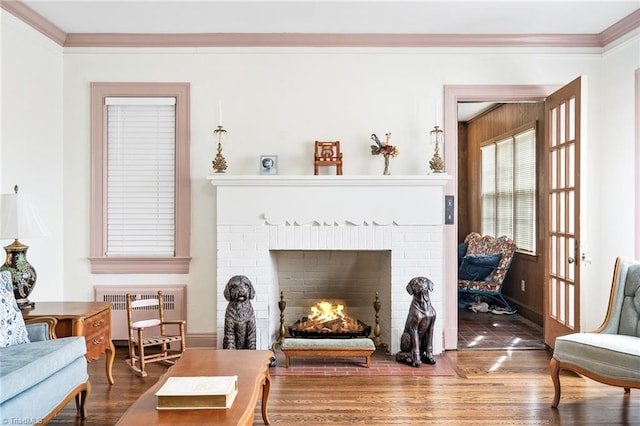 sitting room featuring ornamental molding, a brick fireplace, radiator, and wood finished floors