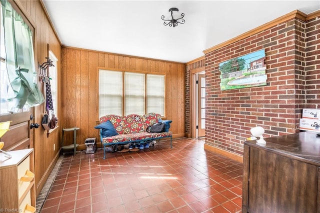 living area featuring crown molding, wood walls, brick wall, and tile patterned floors