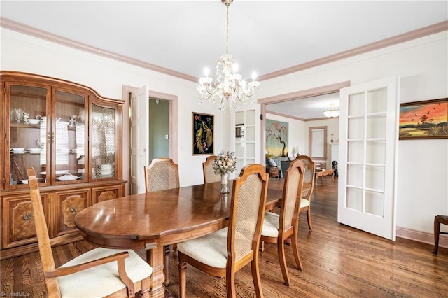 dining area with baseboards, ornamental molding, wood finished floors, and an inviting chandelier