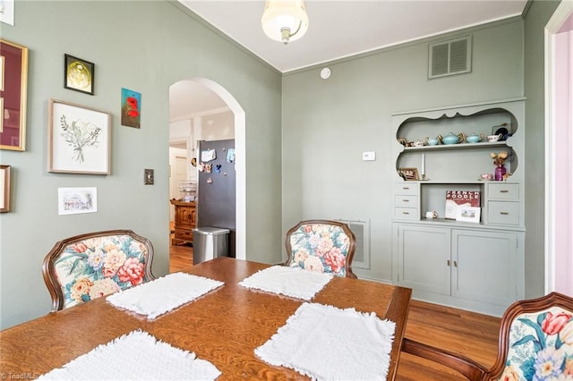 dining space featuring arched walkways, wood finished floors, and visible vents