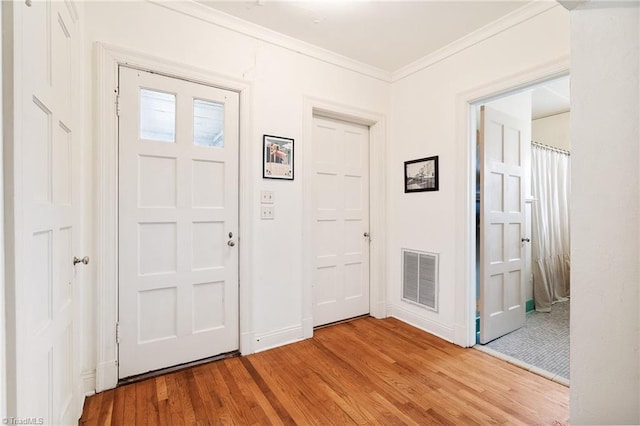 entrance foyer featuring light wood-style floors, baseboards, visible vents, and crown molding