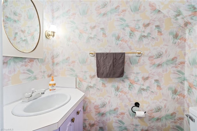 half bathroom featuring vanity and wallpapered walls