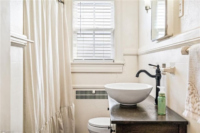 full bath with toilet, vanity, and radiator