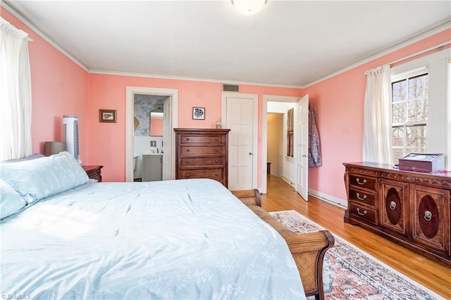 bedroom with light wood-style floors, connected bathroom, visible vents, and ornamental molding