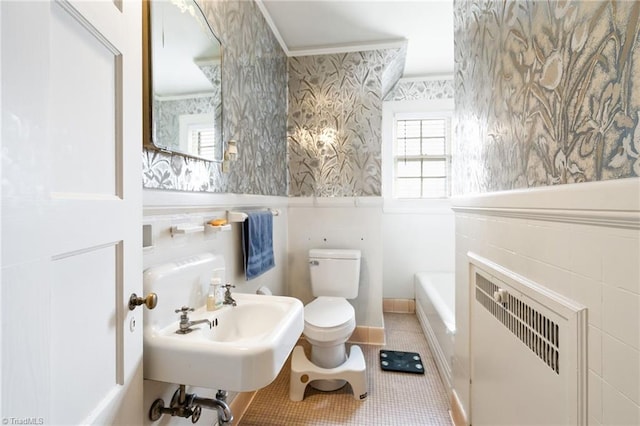 full bath with a tub to relax in, toilet, ornamental molding, wainscoting, and wallpapered walls