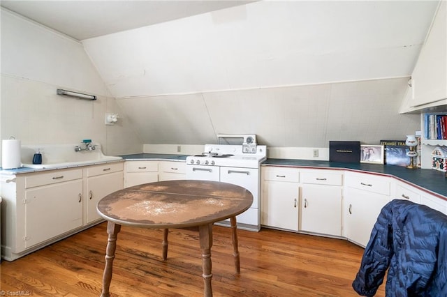 kitchen featuring lofted ceiling, light wood-style floors, white cabinets, washer / clothes dryer, and dark countertops