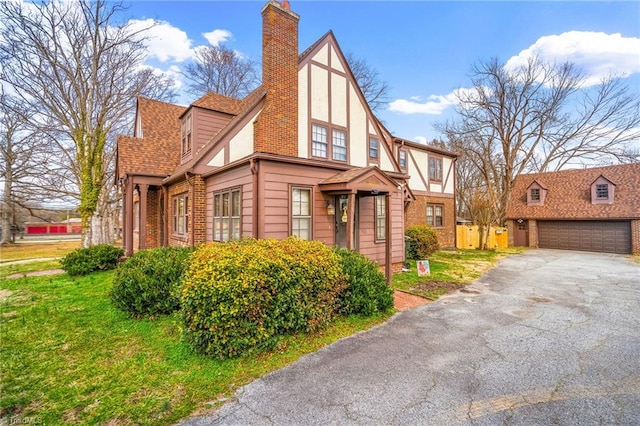 view of property exterior with a garage, brick siding, roof with shingles, stucco siding, and a chimney