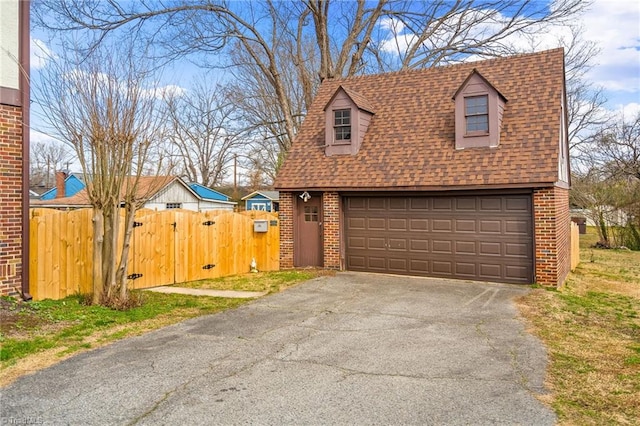 view of front of home with a garage, roof with shingles, a gate, fence, and brick siding