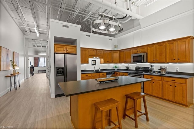 215 S Jefferson Ave Unit 102, West Jefferson, NC 28694 - kitchen with stainless steel appliances, a high ceiling, dark countertops, light wood finished floors, and a center island