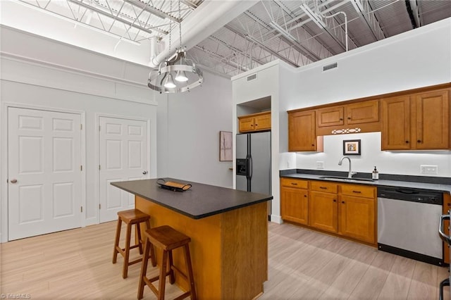 215 S Jefferson Ave Unit 102, West Jefferson, NC 28694 - kitchen featuring stainless steel appliances, a towering ceiling, dark countertops, brown cabinets, and light wood-type flooring