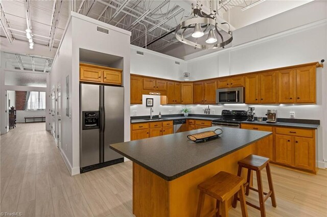 215 S Jefferson Ave Unit 102, West Jefferson, NC 28694 - kitchen with stainless steel appliances, dark countertops, light wood-type flooring, brown cabinets, and a towering ceiling