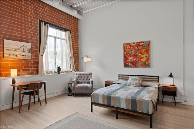 215 S Jefferson Ave Unit 102, West Jefferson, NC 28694 - bedroom featuring brick wall, wood finished floors, a baseboard heating unit, and a high ceiling