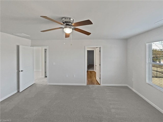 carpeted empty room with ceiling fan and baseboards