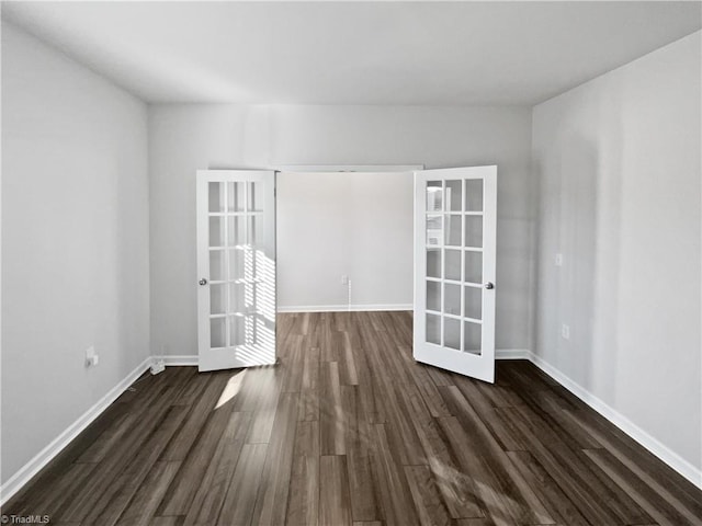 empty room featuring baseboards, dark wood-style flooring, and french doors