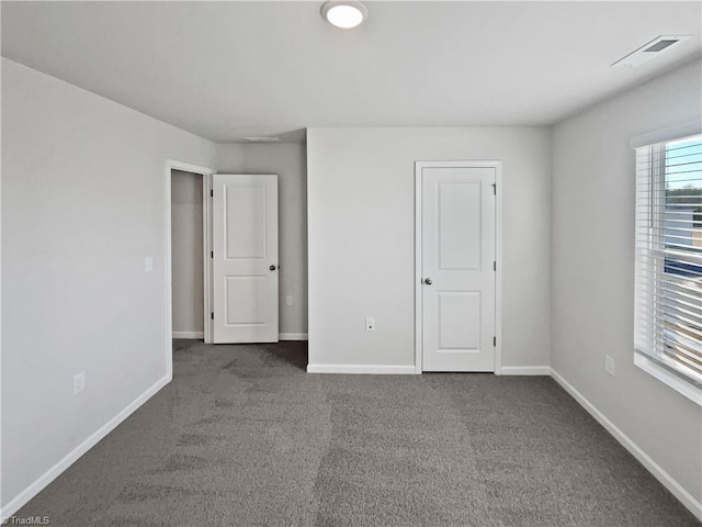 unfurnished bedroom featuring dark colored carpet, visible vents, and baseboards