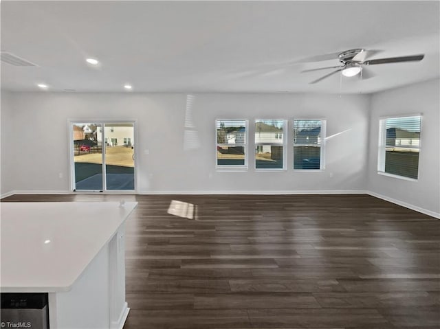 unfurnished living room featuring recessed lighting, a healthy amount of sunlight, dark wood finished floors, and baseboards