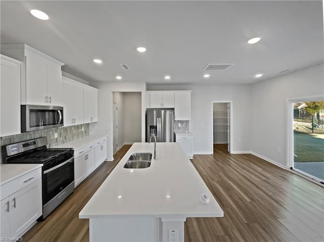 kitchen featuring light countertops, appliances with stainless steel finishes, an island with sink, and a sink