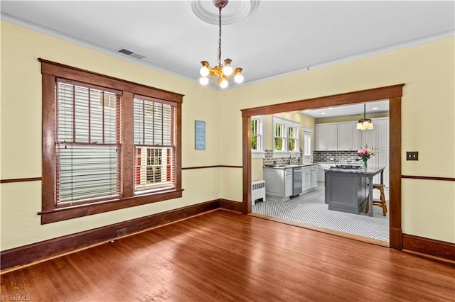 119 Wiley Ave, Salisbury, NC 28144 - unfurnished dining area featuring radiator heating unit, wood finished floors, baseboards, a chandelier, and crown molding
