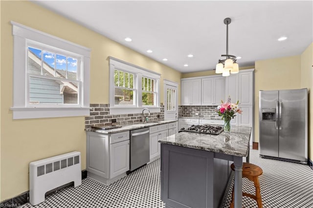 119 Wiley Ave, Salisbury, NC 28144 - kitchen with stainless steel appliances, radiator, a breakfast bar area, backsplash, and light stone countertops