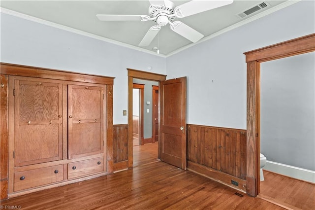 119 Wiley Ave, Salisbury, NC 28144 - unfurnished bedroom featuring a wainscoted wall, crown molding, wood finished floors, ceiling fan, and wood walls