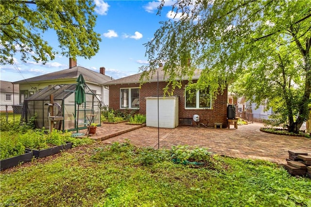 119 Wiley Ave, Salisbury, NC 28144 - rear view of house with a greenhouse, a vegetable garden, brick siding, and an outdoor structure