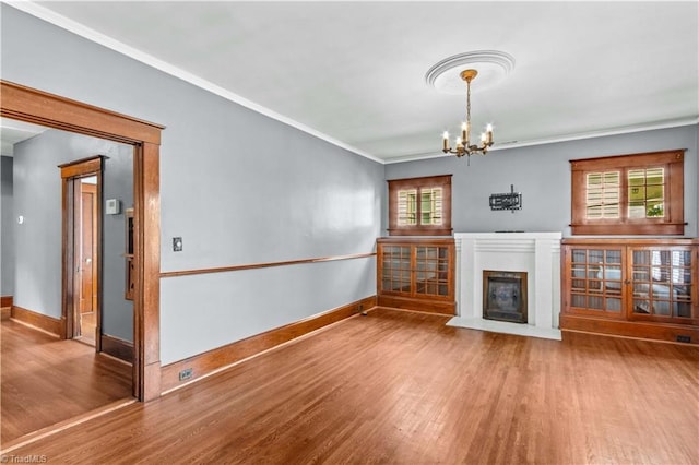 119 Wiley Ave, Salisbury, NC 28144 - unfurnished living room featuring wood finished floors, baseboards, a chandelier, crown molding, and a glass covered fireplace