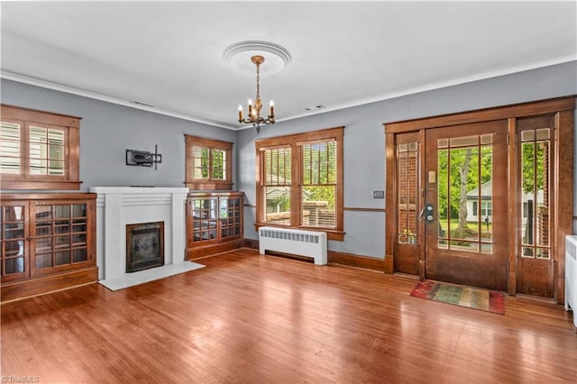 119 Wiley Ave, Salisbury, NC 28144 - unfurnished living room with radiator, a chandelier, healthy amount of natural light, a fireplace with flush hearth, and crown molding