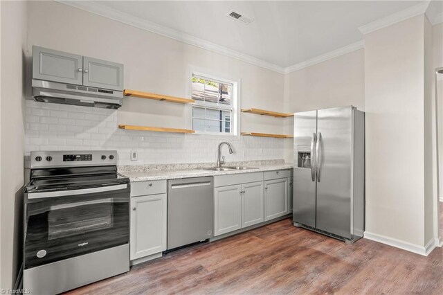 kitchen with light hardwood / wood-style flooring, appliances with stainless steel finishes, sink, tasteful backsplash, and ornamental molding