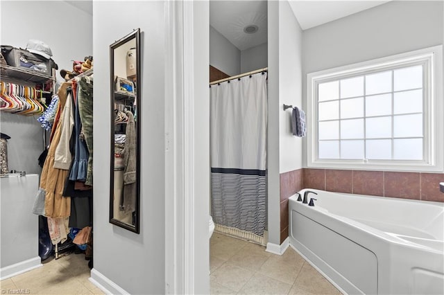 bathroom featuring a walk in closet, a shower with curtain, tile patterned flooring, baseboards, and a bath