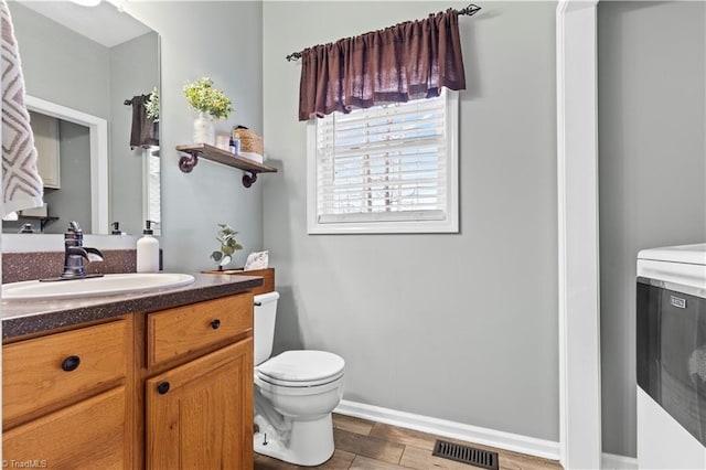 bathroom with visible vents, toilet, vanity, wood finished floors, and washer / dryer