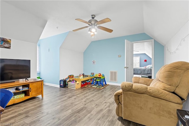 recreation room with baseboards, visible vents, a ceiling fan, light wood-style flooring, and vaulted ceiling