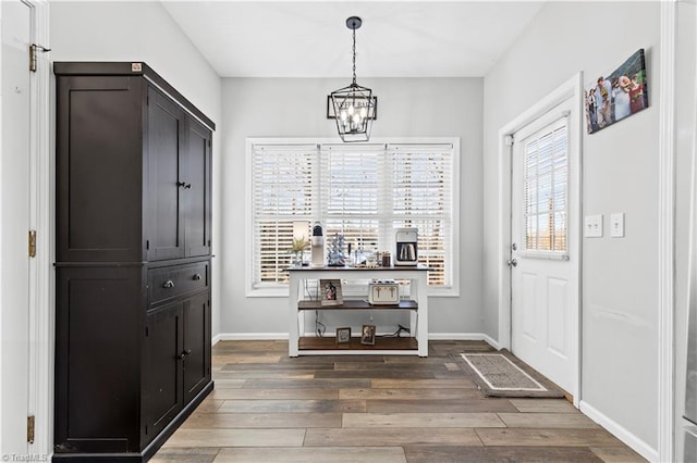 interior space with a notable chandelier, baseboards, and wood finished floors