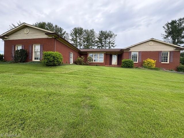ranch-style house with a front yard and brick siding