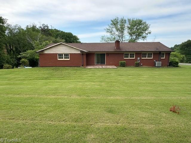 view of front facade featuring a front yard and central air condition unit
