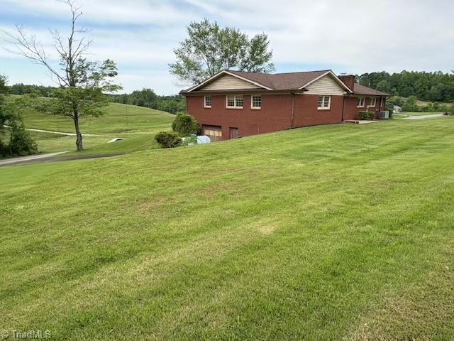view of property exterior with a garage, a lawn, and a chimney